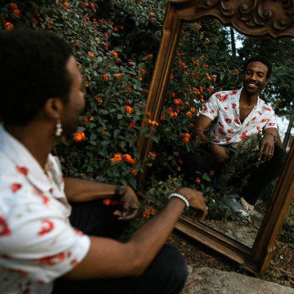 Person meditating peacefully outdoors with a serene smile.